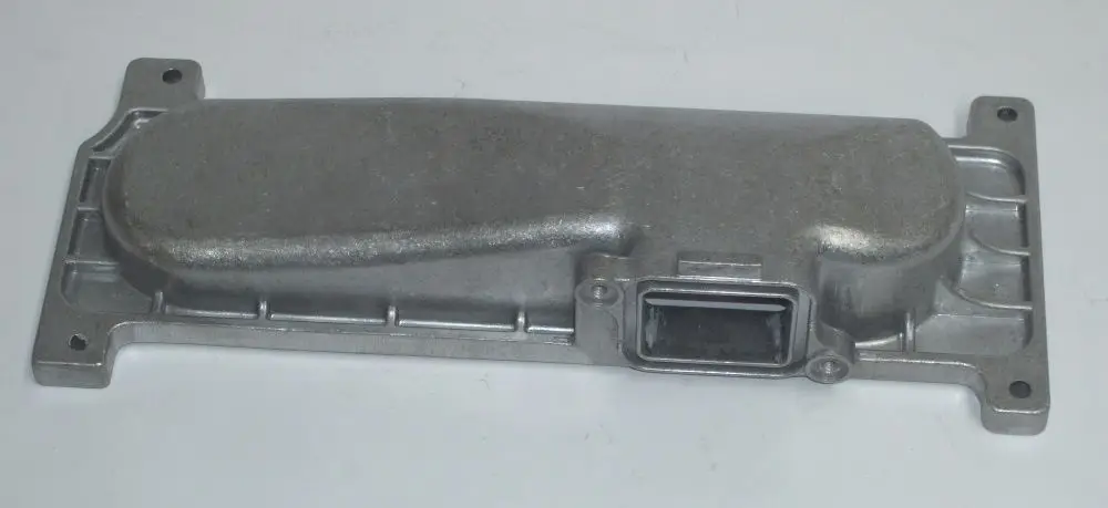 Metallene Abdeckung für einen Brenner, möglicherweise von Daikin, mit einer ovalen Form und Befestigungslöchern an den Seiten, auf einer neutralen Oberfläche.